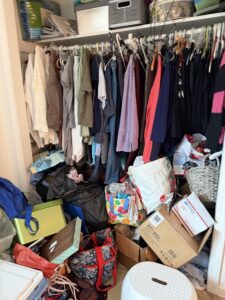 photo of a messy closet space with clutter on the floor and messy hangers and clothes